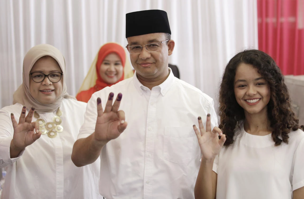 Gubernatorial candidate Anies Baswedan, center, his wife Fery Farhati Ganis, left, and daughter Mutiara show their ink-dipped fingers. (AP Photo/Dita Alangkara)