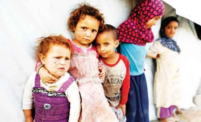 War-displaced Yemeni children stand next to a tent at a camp near Sanaa. (Reuters)