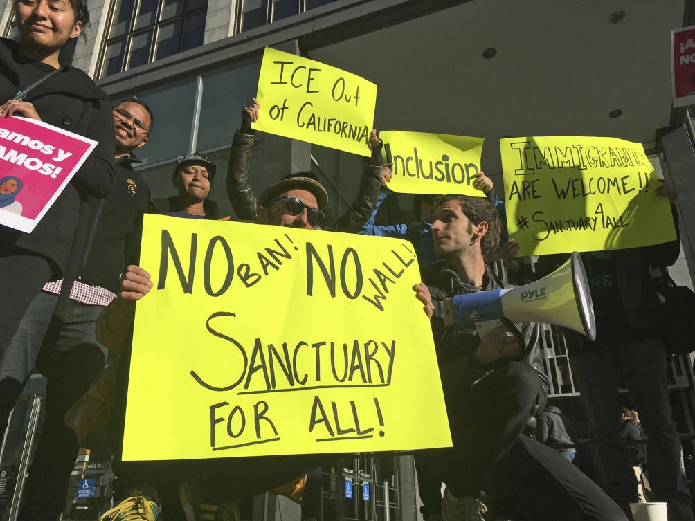 Protesters hold up signs outside a courthouse where a federal judge will hear arguments in the first lawsuit challenging President Donald Trump's executive order to withhold funding from communities that limit cooperation with immigration authorities. (AP)
