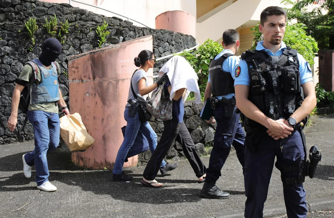 French gendarmes and police officers escort a person (C, hidden face) on April 27, 2017 in Saint-Denis-de-la-Reunion, on the French Indian Ocean island of Reunion, after a man suspected of being a radicalised Islamist shot and wounded two policemen. (AFP)