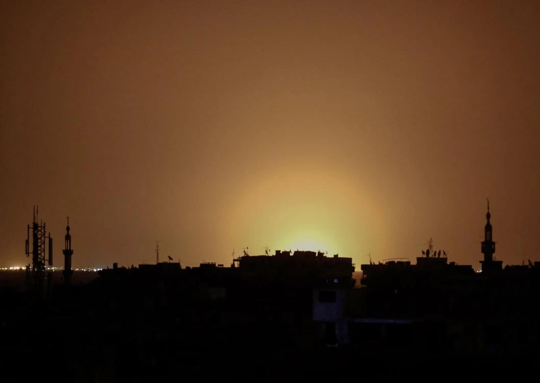 A photo taken from the rebel-held town of Douma shows flames rising in the distance which are believed to be coming from Damascus International Airport following an explosion early in the morning of April 27, 2017. (AFP)
