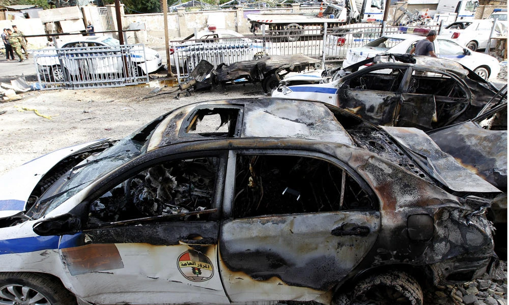 Burnt police cars are seen at the site of a blast in the Iraqi capital Baghdad on Saturday. (AFP / SABAH ARAR)