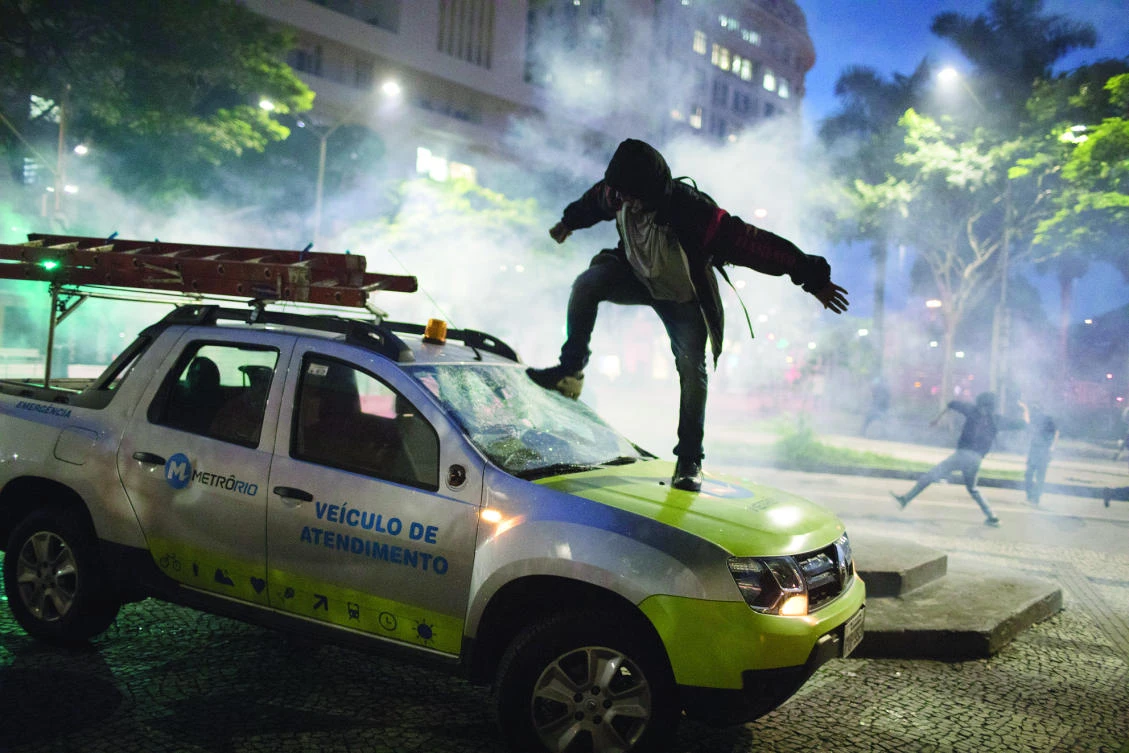 A demonstrator breaks the windshield of a truck during Friday's general strike in Rio de Janeiro, Brazil. (AP)