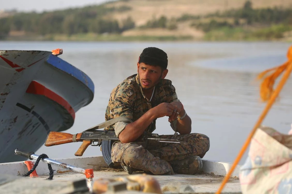 A member of the US-backed Syrian Democratic Forces (SDF), made up of an alliance of Arab and Kurdish fighters, sits on the edge of a boat at the Tabqa dam on April 29, 2017, which has been recently partially recaptured, as part of their battle for the Daesh stronghold in nearby Raqa. (AFP)