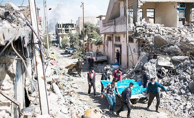 This March 24, 2017 photo, residents carry the body of several people killed in airstrikes during fighting between Iraq security forces and Daesh on the western side of Mosul, Iraq. (AP)