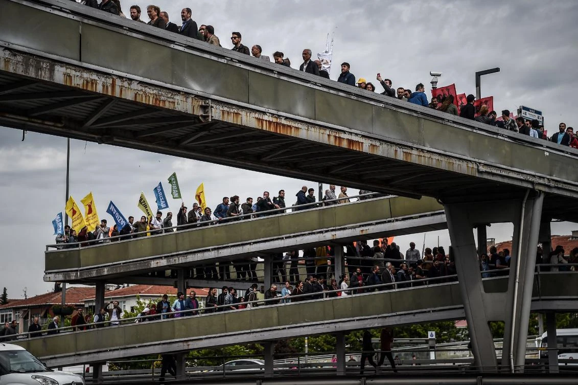 People walk on a bridge as they gather in Bakirkoy district as part of the the May Day rally, in Istanbul, on May 1, 2017. / AFP / OZAN KOSE