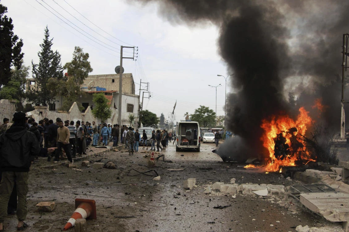 Syrian citizens and civil defense workers gathering next of burning car at the explosion scene, in Azaz town, north Syria, Wednesday, May 3, 2017. (Azaz Media Office via AP)