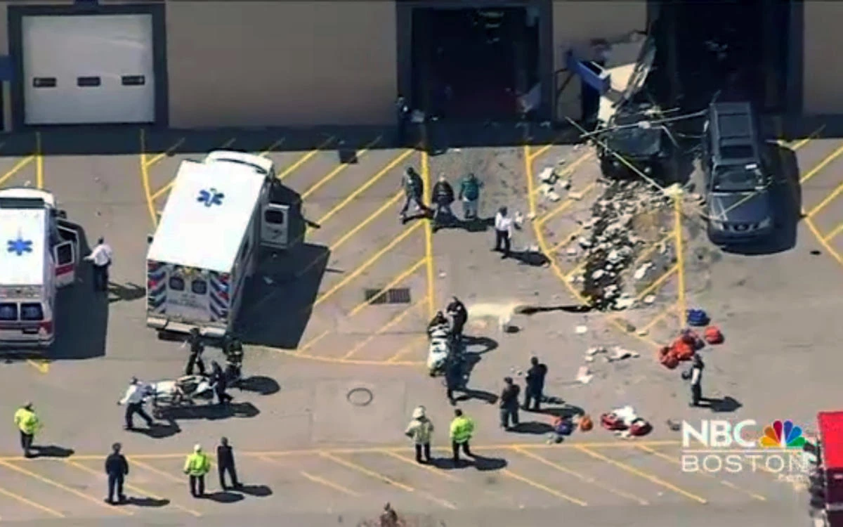 This still image from video provided by NBC Boston, emergency personnel work at the scene after a vehicle suddenly accelerated at an auto auction and struck several people before it crashed through a wall of the building, Wednesday, May 3, 2017, in Billerica, Massachusetts, United States. (NBC Boston via AP)