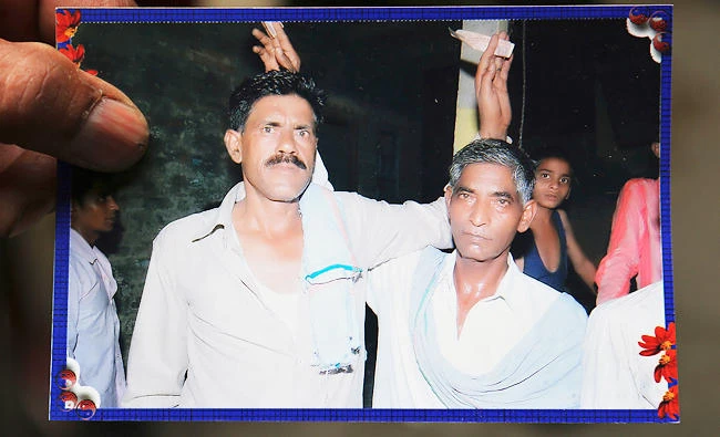 Vakil Ahmad displays a photograph of his father Ghulam Mohammad, right, who was beaten to death on Tuesday, at their residence in Sohi village, in Uttar Pradesh state's Bulandshahar district, India, on May 3, 2017 photo. (AP)