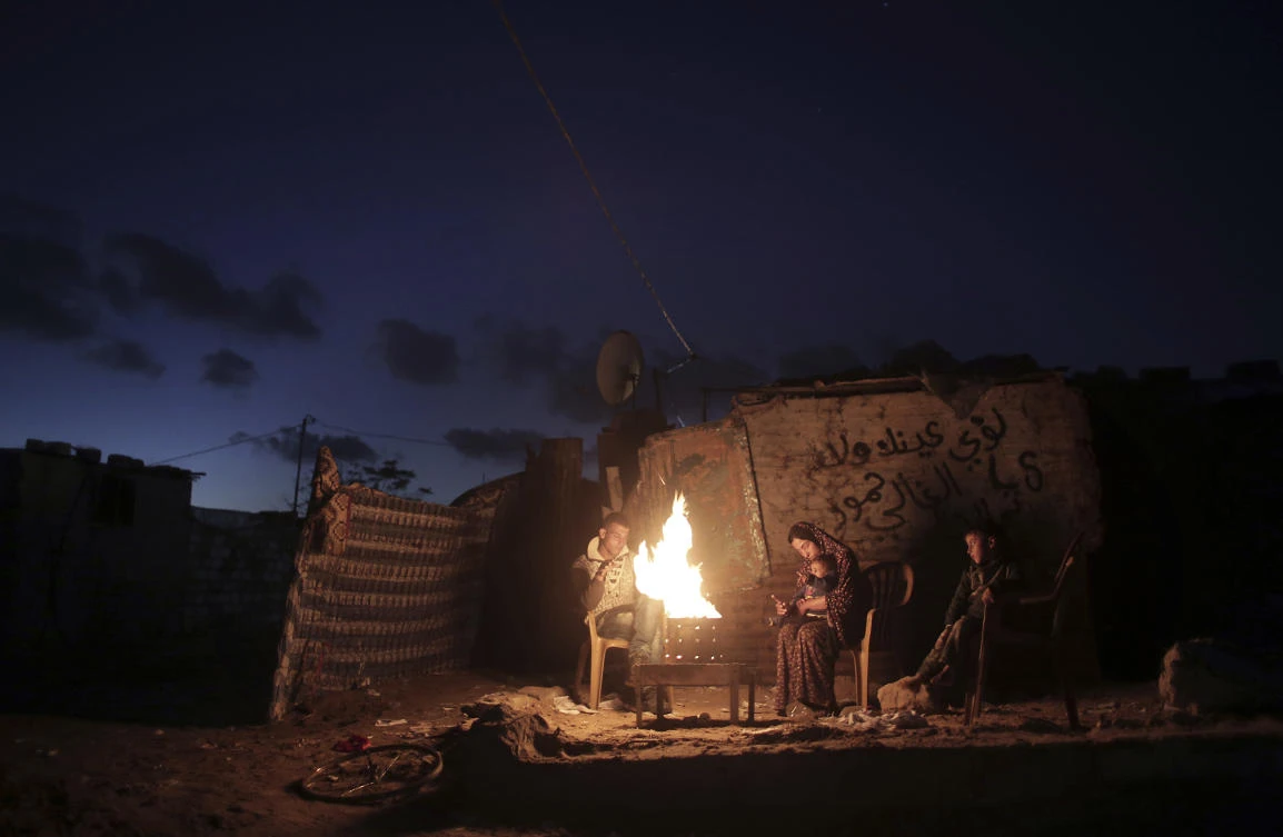 A Palestinian family warm themselves up with a fire outside their makeshift house during a power cut in a poor neighborhood in the southern Gaza Strip, in this Jan. 15 file photo. (AP)