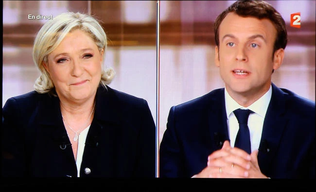 A television screen shows the live broadcast television debate with French centrist presidential candidate Emmanuel Macron, right, and far-right candidate Marine Le Pen, on Wednesday, in a bar of Biarritz, southwestern France. (AP)