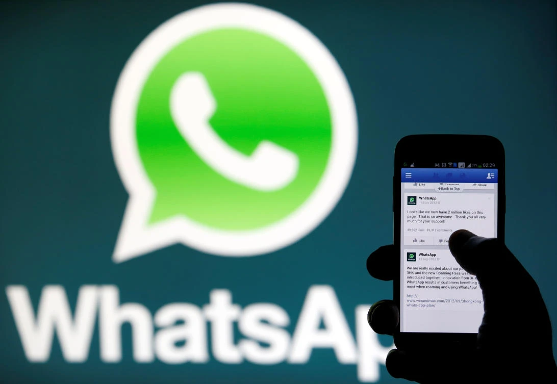 A WhatsApp logo is seen behind a phone that is logged on to Facebook in the central Bosnian town of Zenica. (REUTERS/Dado Ruvic/File Photo)