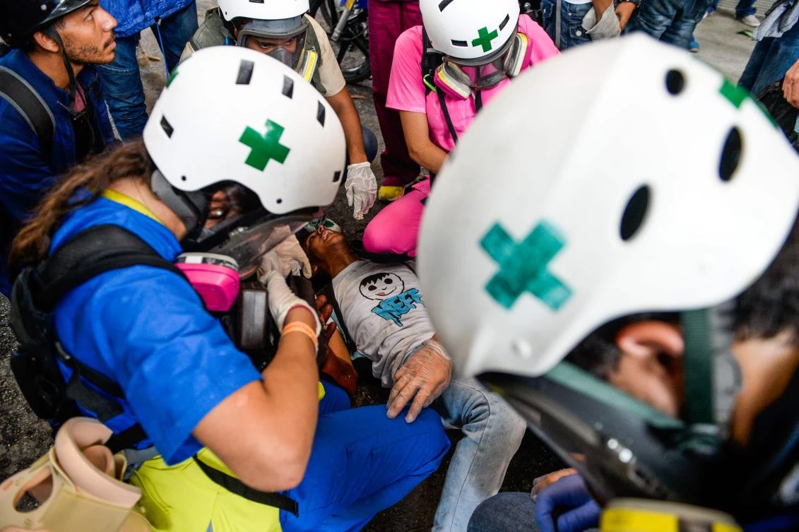A demonstrator wounded during clashes with riot police is assisted by medics during a protest against in Caracas on Wednesday. (AFP)