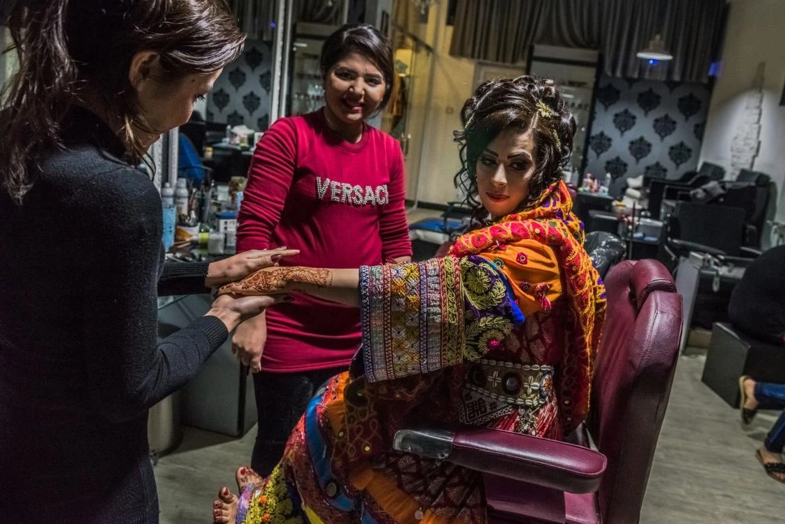 In this photograph taken on March 23, 2017, an Afghan bride dressed in a traditional wedding gown sits as a beautician applies moisturiser ahead of her wedding party at a beauty parlour in Kabul. (AFP)