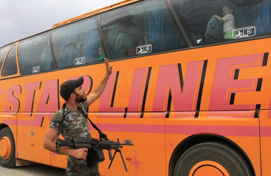 An opposition fighter waves at civilian arriving by bus. (AFP)