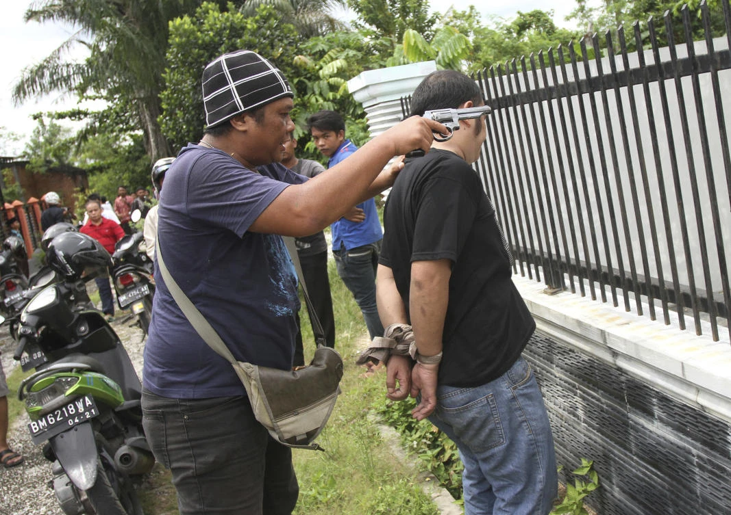 A plain-clothed police officer arrest an inmate who escaped from Sialang Bungkuk Prison in Pekanbaru, Riau province, Indonesia, Friday, May 5, 2017. Hundreds of police and soldiers were deployed to search for some scores of inmates who escaped Friday from the overcrowded prison on Sumatra island. (AP Photo)