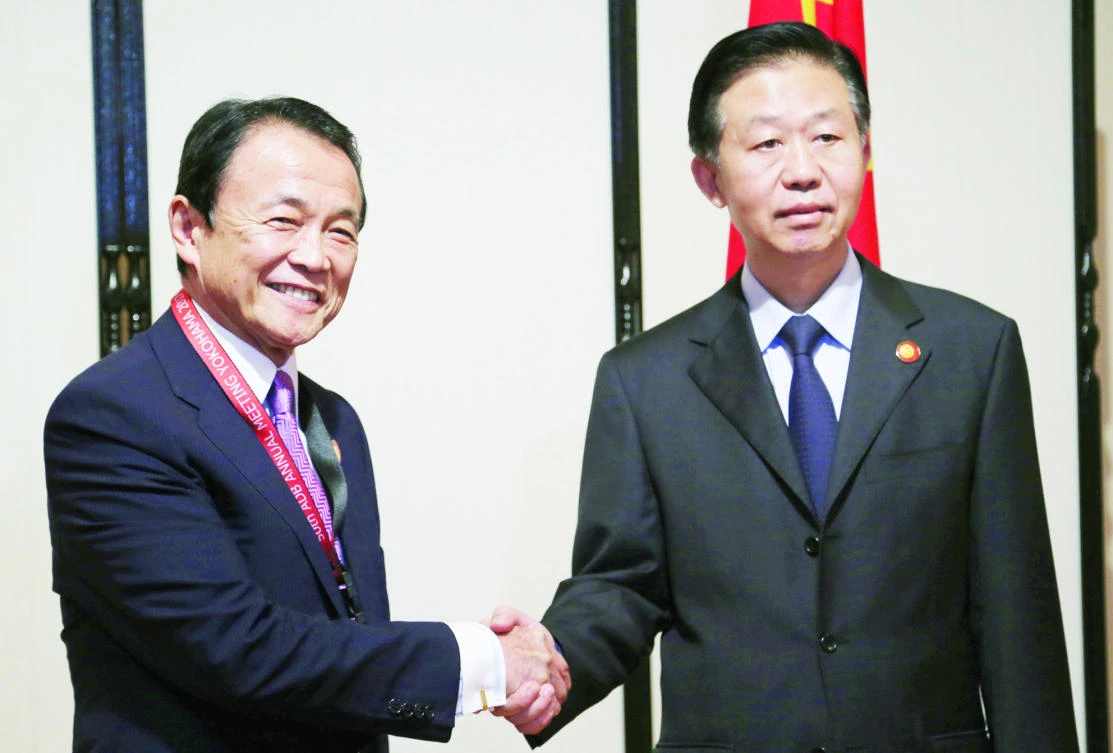 Chinese Finance Minister Xiao Jie, right, shakes hands with his Japanese counterpart Taro Aso during their bilateral meeting, on the sidelines of Asian Development Bank (ADB) annual meeting, in Yokohama, Japan on Saturday. (Reuters)