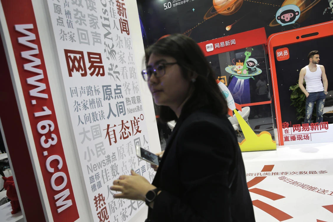 In this Thursday, April 28, 2016, photo, a woman visits a display booth for the Chinese Internet portal 163.com promoting its news section, at the Global Mobile Internet Conference (GMIC) in Beijing. China is tightening rules for online news as the country’s censors try to control the flood of information being spread through instant-messaging apps, blogs and other sources. (AP)