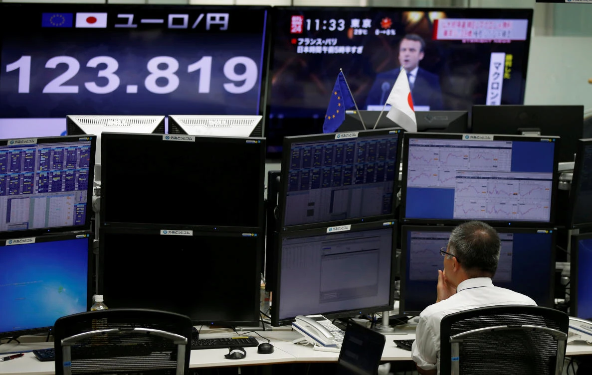 An employee of a foreign exchange trading company works near monitors showing French President-elect Emmanuel Macron on TV news and the Japanese yen's exchange rate against the euro in Tokyo, Japan. (Reuters)