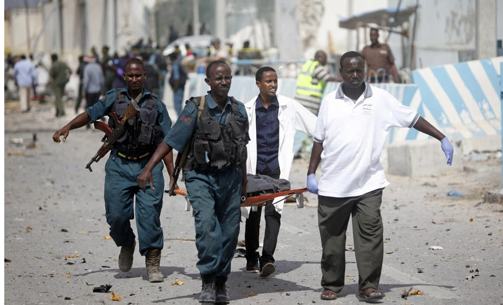 In this July 26, 2016 photo, United Nations office guards and Somalian soldiers carry the body of a person who was killed in a suicide car bomb outside the UN's office in Mogadishu, Somalia. Another car bomb on Monday killed at least five people in central Mogadishu. (AP file photo)