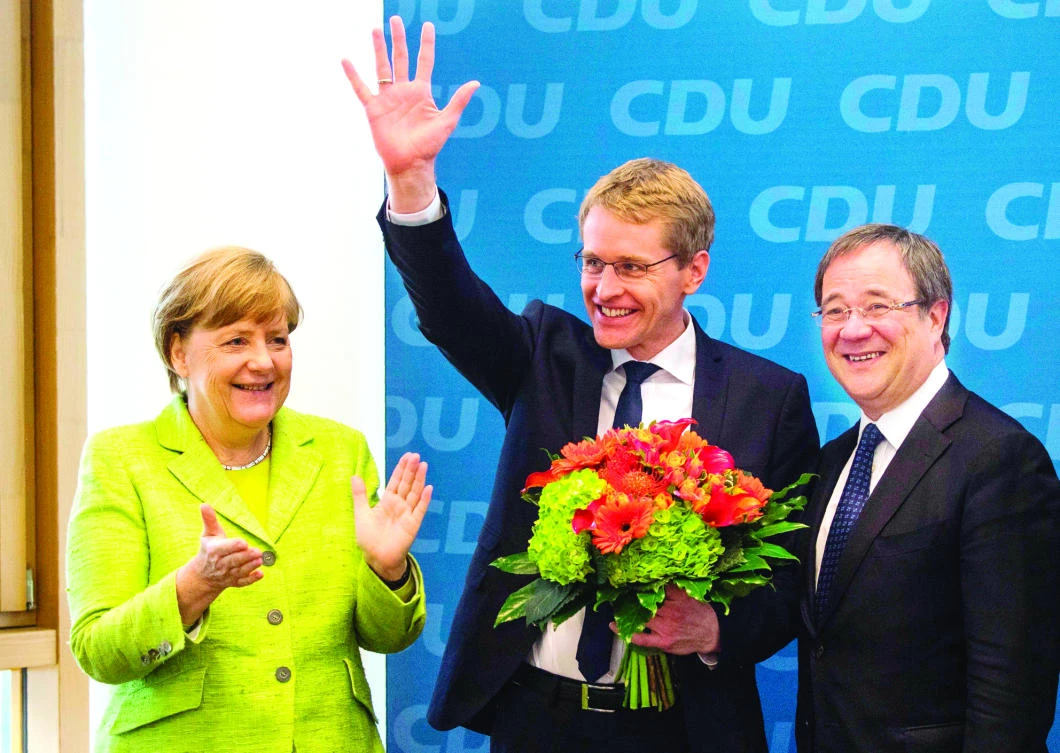 From left: German Chancellor and Christian Democratic Union (CDU) leader Angela Merkel, CDU candidate in regional elections in Schleswig-Holstein Daniel Guenther and CDU candidate in upcoming elections in North Rhine-Westphalia Armin Laschet celebrate prior to a meeting of the CDU leadership at the party’s headquarter in Berlin on Monday. (AFP)