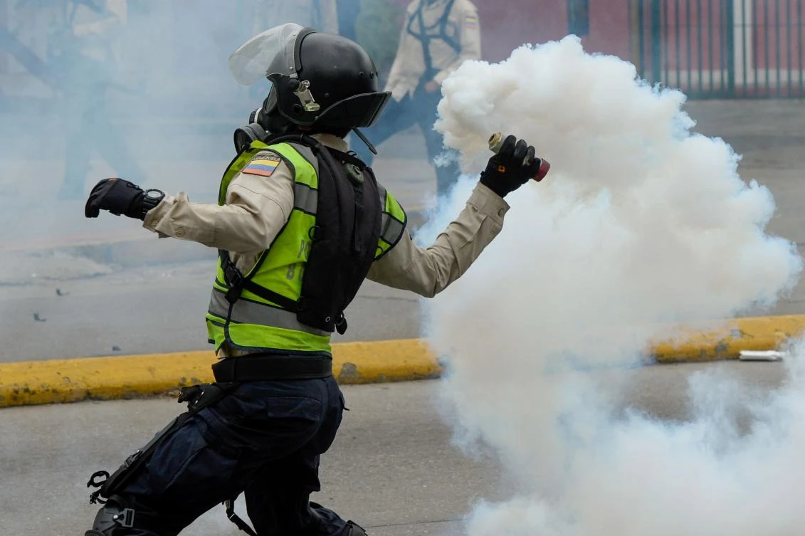 A riot policeman hurls a tear gas canister at opposition activists. (AFP)