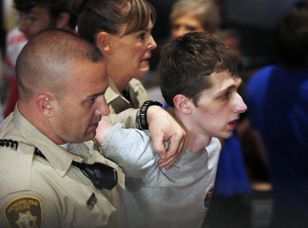 In this June 18, 2016 photo, police remove Michael Sandford as then Republican presidential candidate Donald Trump speaks at the Treasure Island hotel and casino in Las Vegas. (AP Photo/John Locher, File)