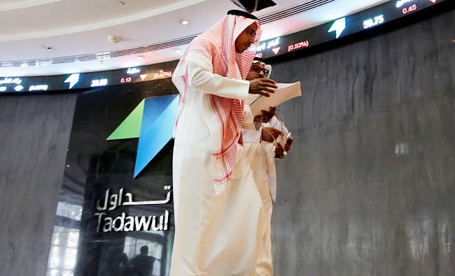 Saudi men walk at the Tadawul Saudi Stock Exchange, in Riyadh, Saudi Arabia, in this file photo. (AP)