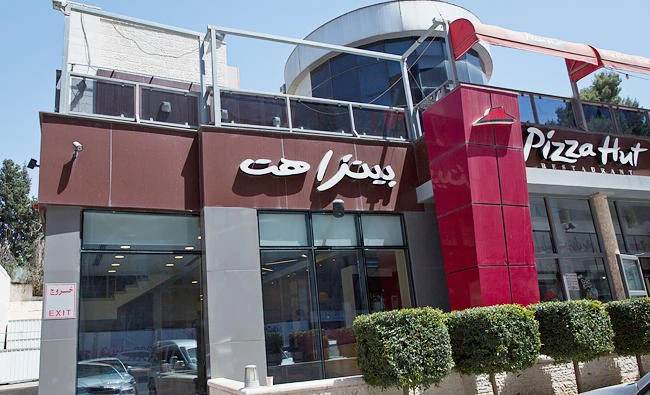 A woman walks by a Palestinian branch of the Pizza Hut company, in the West Bank city of Ramallah, on Wednesday. (AP)