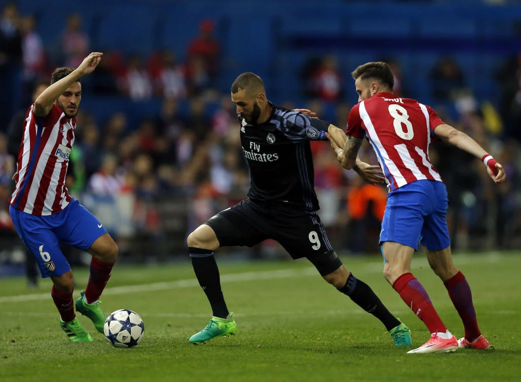 Real Madrid's Karim Benzema, center, battles for the ball with Atletico's Koke, left, and Saul Niguez during a Champions League semifinal, 2nd leg soccer match between Atletico de Madrid and Real Madrid, in Madrid, Spain, Wednesday . (AP)
