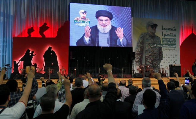 Hezbollah leader Sayyed Hassan Nasrallah addresses his supporters from a screen, during a ceremony in Beirut on Thursday marking a year after Hezbollah commander Mustafa Badreddine (picture on banner) was killed in an attack in Syria. (REUTERS/Aziz Taher)