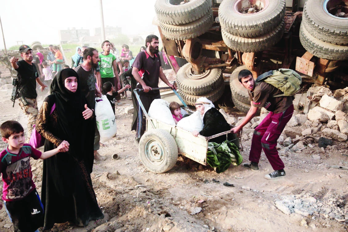 An elderly woman and a child are pulled on a cart as civilians flee heavy fighting between Daesh militants and Iraqi special forces in western Mosul, Iraq. (AP)