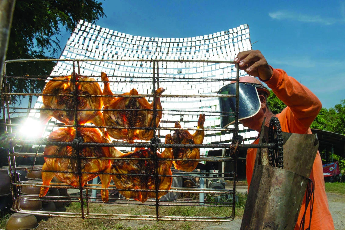 Thai food vendor Sila Sutharat turns the grates on a cart loaded with chicken as he cooks the white meat with rays of sun reflected on an oversized mirror panel, in the Petchaburi province, south of Bangkok. (AFP)