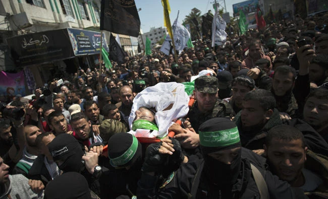 FILE -- In this March, 25, 2017 file photo, members of the Qassam brigade, the militia wing of Hamas, carry the body of Mazen Faqha, a top militant commander, during his funeral in Gaza City. Ismail Haniyeh, Hamas' supreme leader, announced Thursday May 11, 2017, the arrest of a suspect in the shooting death of Faqha iAP Photo/ Khalil Hamra, File)