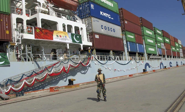 In this Nov. 13, 2016 file photo, a Pakistani soldier stands guard while a loaded Chinese ship prepares to depart from Gwadar port that links to China's far western region on a new international route exporting goods to the Middle East and Africa, about 700 kilometers west of Karachi. Pakistan. (AP Photo/Muhammad Yousuf, File)