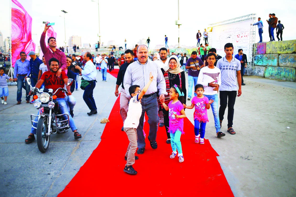 Palestinians walk on the red carpet during a film festival showcasing films focusing on human rights, in Gaza City. (AFP)