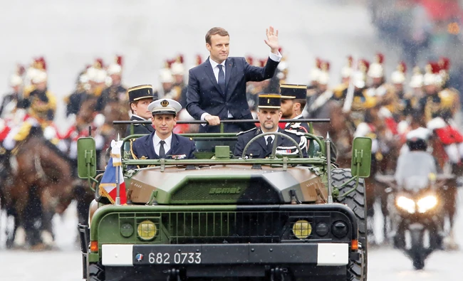 Newly elected French President Emmanuel Macron waves as he parades in a military car on the Champs Elysees Avenue after his formal inauguration ceremony on Sunday in Paris. (AFP)