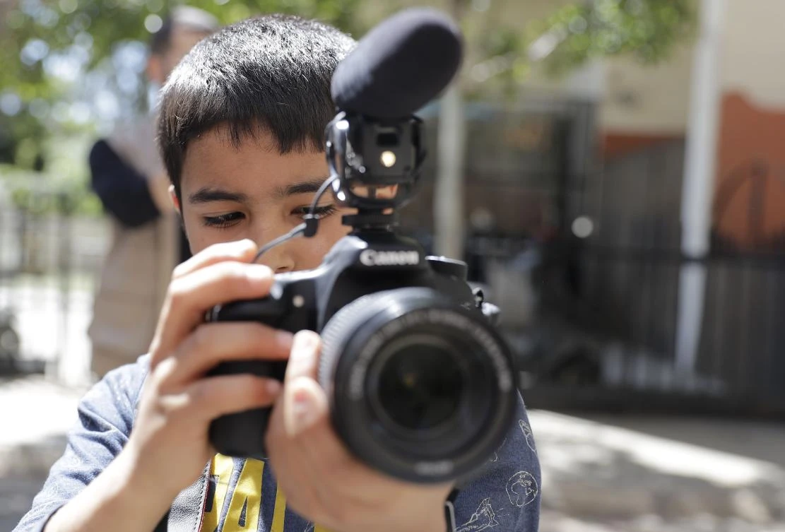 Eleven-year-old Syrian refugee Mostafa Abdallah from the Syrian town of Minbej films his friends who are acting in Beirut's southern suburb of Shatila on April 5, 2017 as part of a refugee programme called the Refugee Film Project. (AFP)