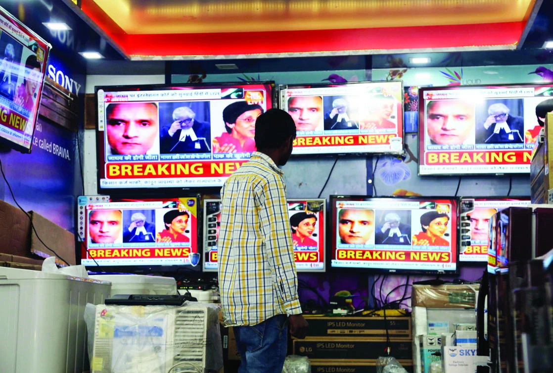 A boy watches a television show about the hearing of Indian naval officer Kulbhushan Jadhav in Jammu, India, on Monday. (AP)