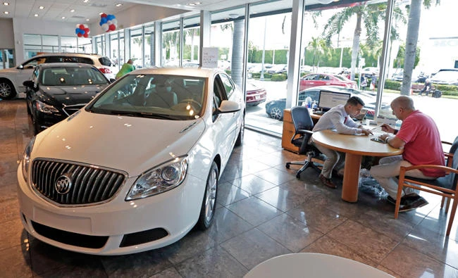 In this April 26, 2017, photo, client specialist Felipe A. Perdomo, left, closes a deal with customer John Tsialas at a GMC Buick dealership in Miami. (AP)