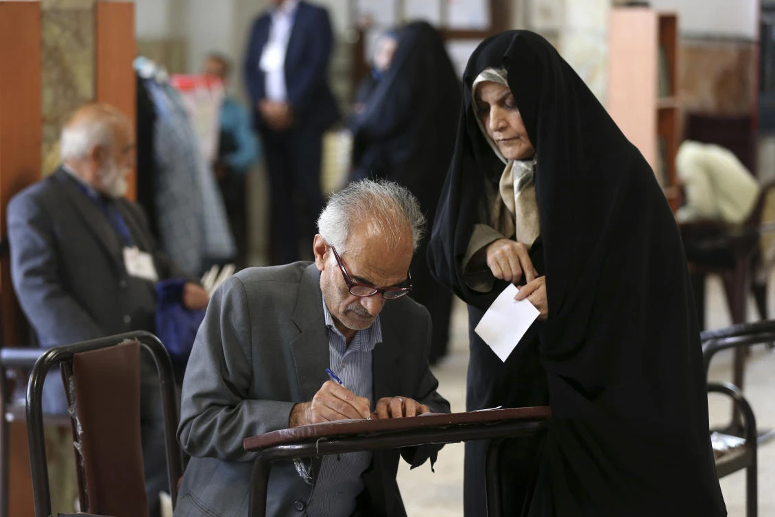 A man fills out his ballots to vote in the presidential and municipal council election in Tehran, Iran. (AP)