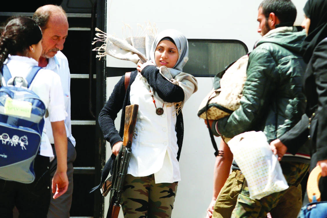 A rebel woman fighter fixes her headscarf as she carries her weapon before boarding a bus, as rebel fighters and their families evacuate the besieged Waer district, after an agreement was reached between rebels and Syria's army, in Homs, on Saturday. (Reuters)
