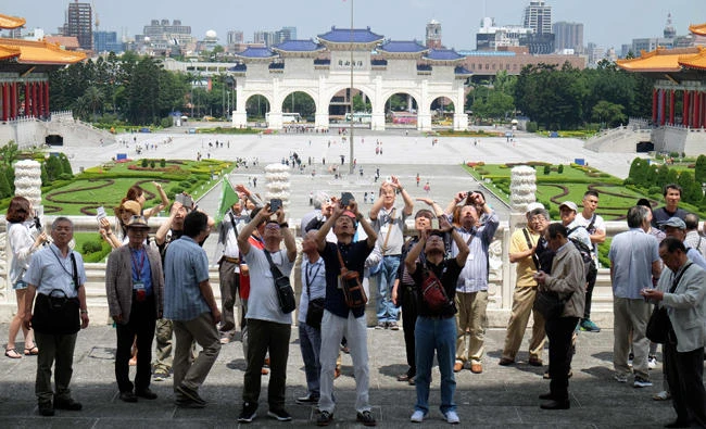 Tourists take photos at the Chiang Kai-skek Memorial Hall in Taipei on May 18, 2017. Visitor numbers to Taiwan fell in the first quarter, dragged down by a 42 percent plunge in arrivals from China as relations worsen across the strait. (AFP / SAM YEH)
