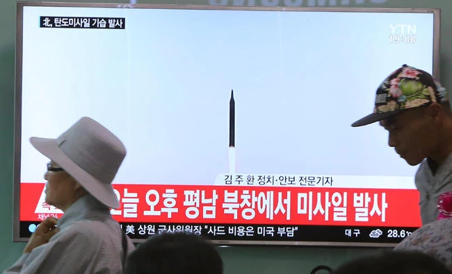 People walk by a TV news program showing a file image of a missile launch conducted by North Korea, at the Seoul Railway Station in Seoul, South Korea, on Sunday. (AP)
