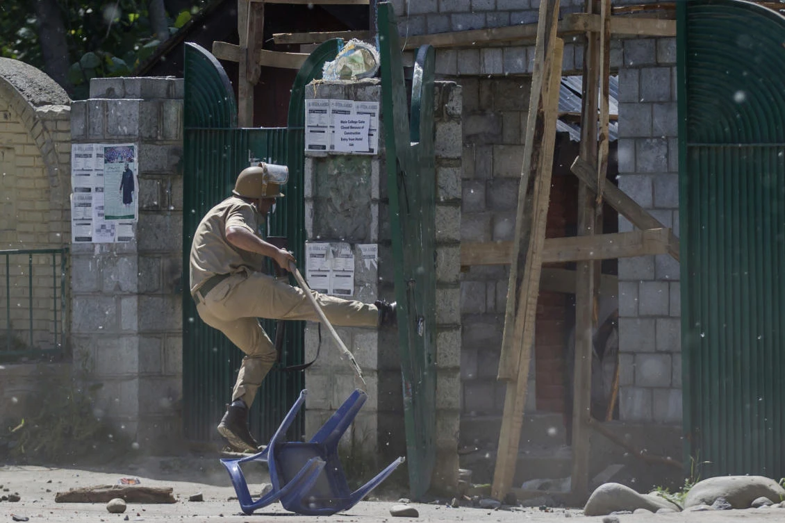 An Indian policeman kicks the gate of a college during a clash with Kashmiri students in Srinagar, Indian controlled Kashmir, on Tuesday. Indian authorities. India announced Tuesday it had fired mortars at Pakistani army posts across their disputed border in Kashmir. (AP Photo/Dar Yasin)