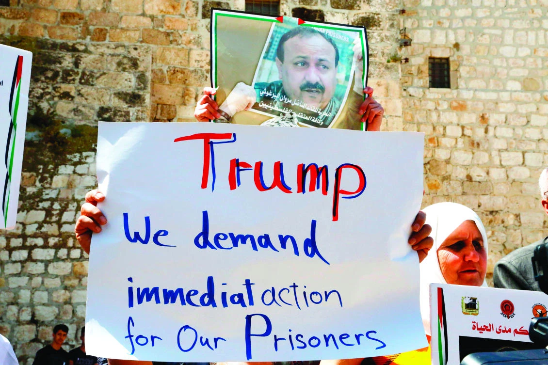 Palestinian protesters shout slogans and hold placards outside the Church of the Nativity in Bethlehem during a demonstration in support of prisoners refusing food in Israeli jails, on Tuesday during a visit of US President Donald Trump to the West Bank town. (AFP)