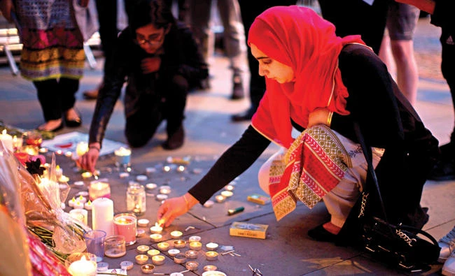 A woman lights candles after a vigil in Albert Square, Manchester, England, on Tuesday. (AP)