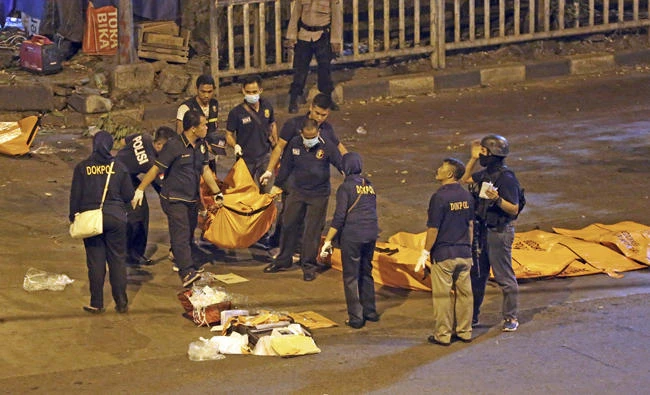 Police officers carry a body bag from the site where explosions reportedly went off near a bus terminal in Jakarta, Indonesia, on Thursday. (AP Photo/Dita Alangkara)
