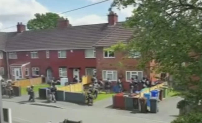 This still image from a video taken by Manchester residents show British police raiding a residence on Wednesday apparently in search of suspects in the Manchester Arena explosion which killed at least 22 people on Monday night. (Via AP)