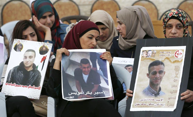 Palestinian women hold portraits of relatives imprisoned in Israeli jails during a protest in front of the Red Cross offices in east Jerusalem on Thursday. (AFP)